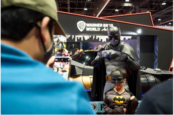 Kid wearing Batman cosplay taking photos with another Adult Batman cosplay.